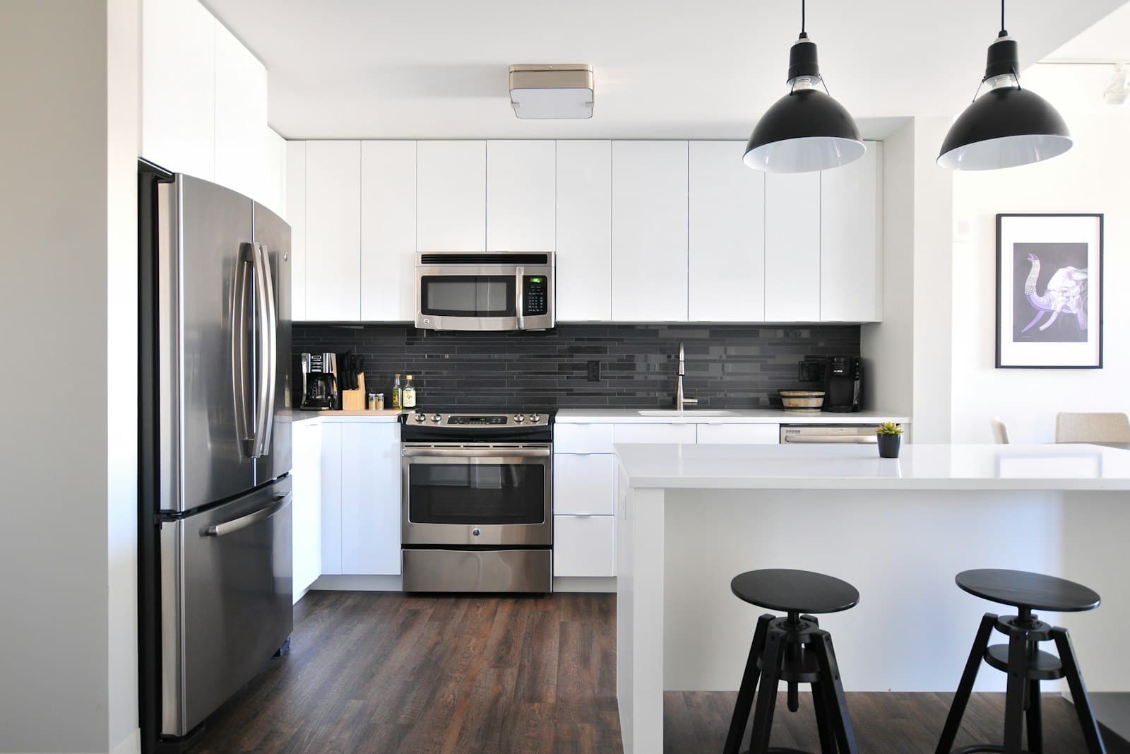 Dapur modern berwarna putih dengan island dan kursi bar