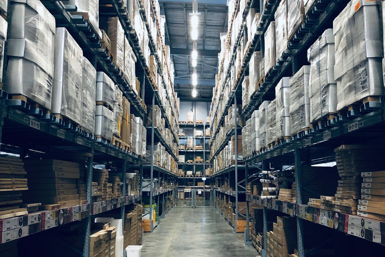 Lorong gudang logistik dengan rak material bertingkat tinggi